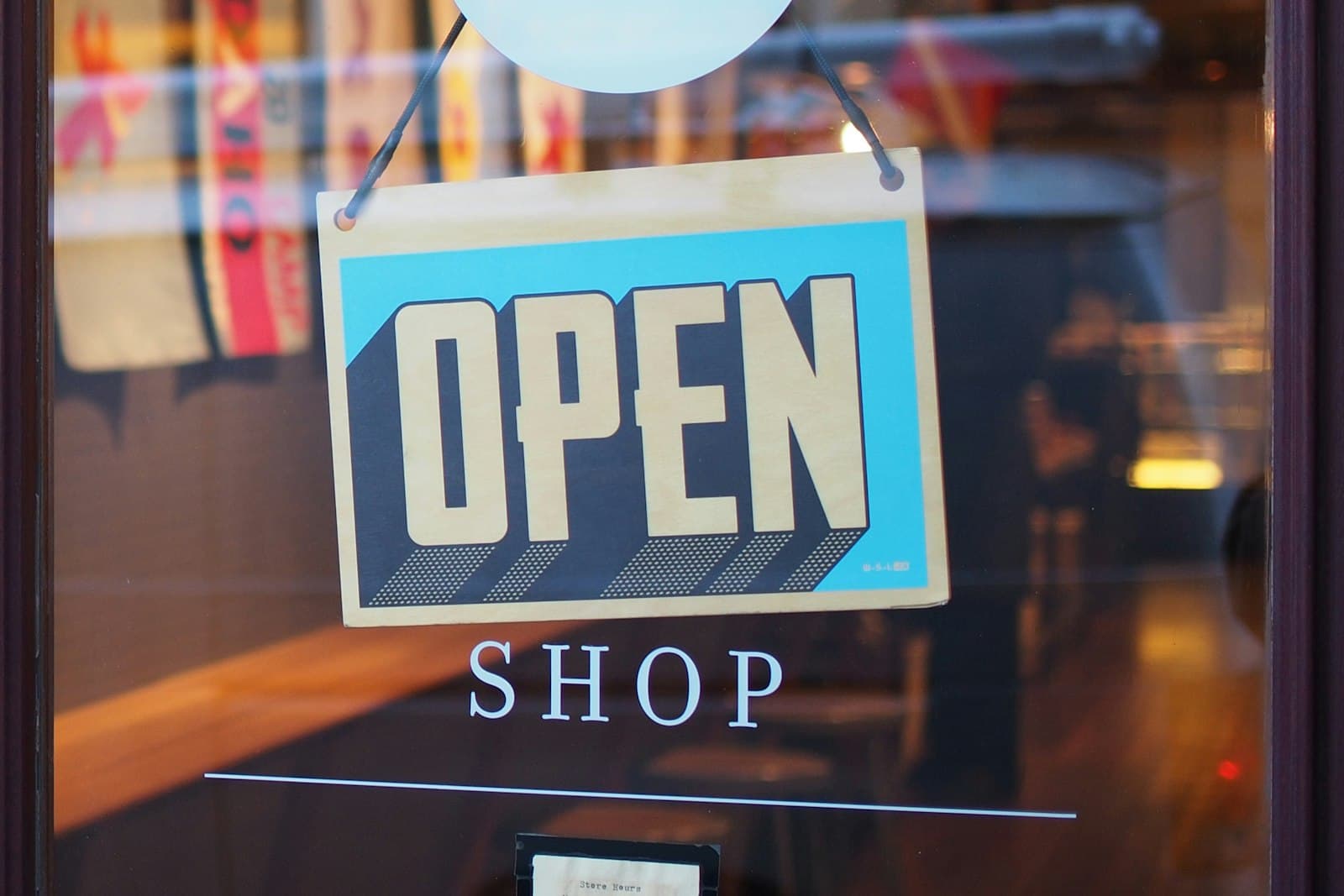 An open shop sign hanging in a storefront window.