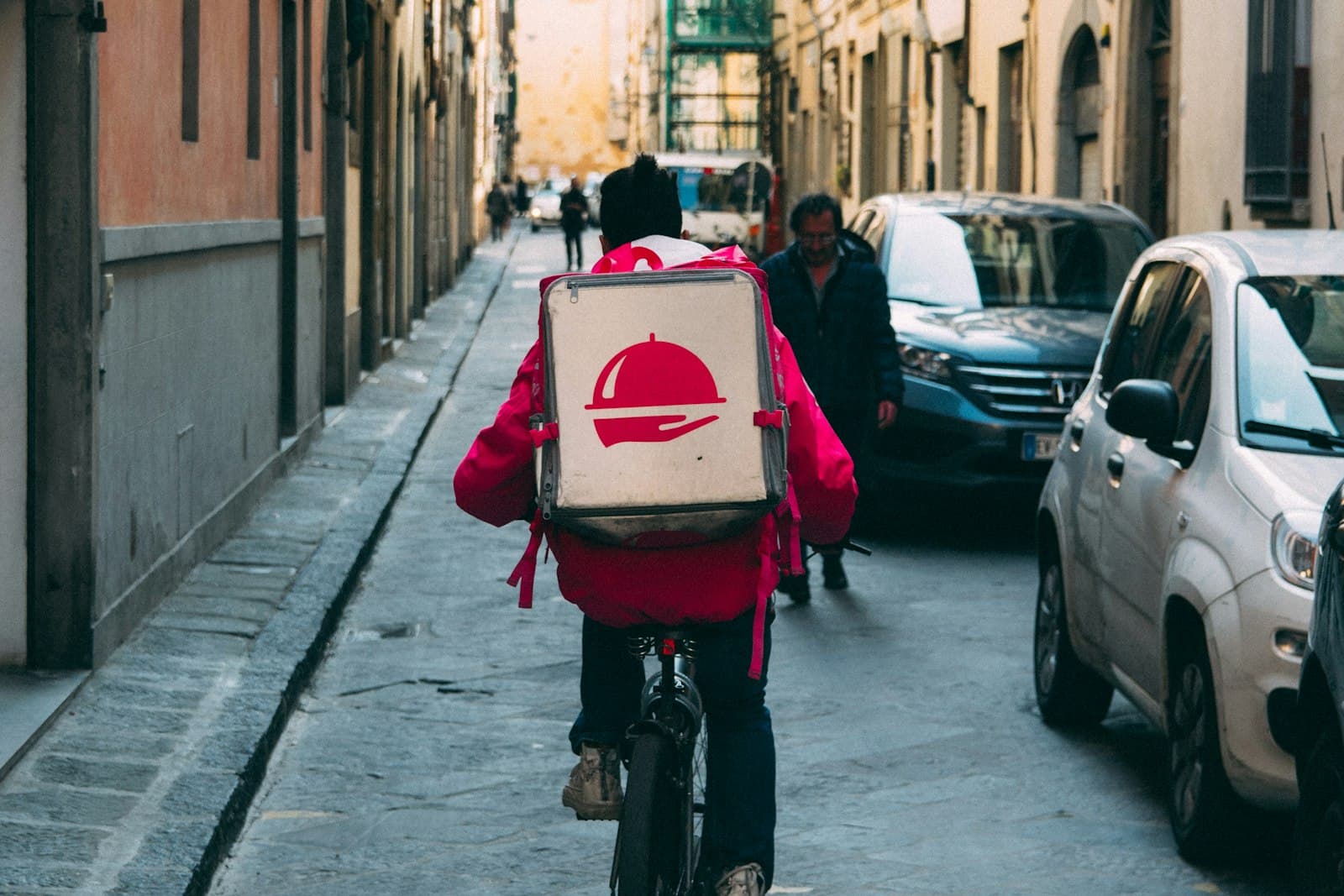 A courier cycling through a narrow street on a local delivery round.