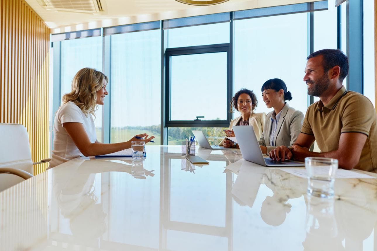 Hiring conversation around a conference table with laptops.